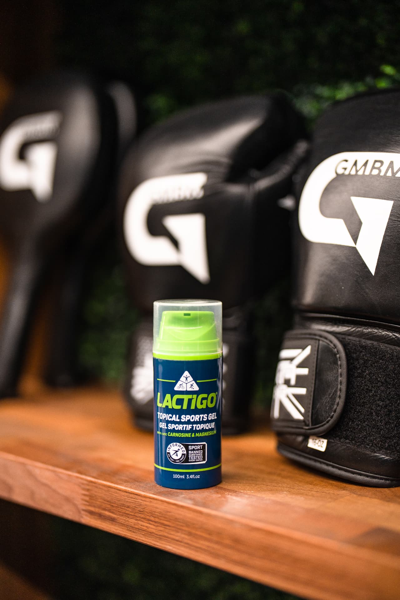 LactiGo topical sports gel bottle on a bench in front of boxing gloves