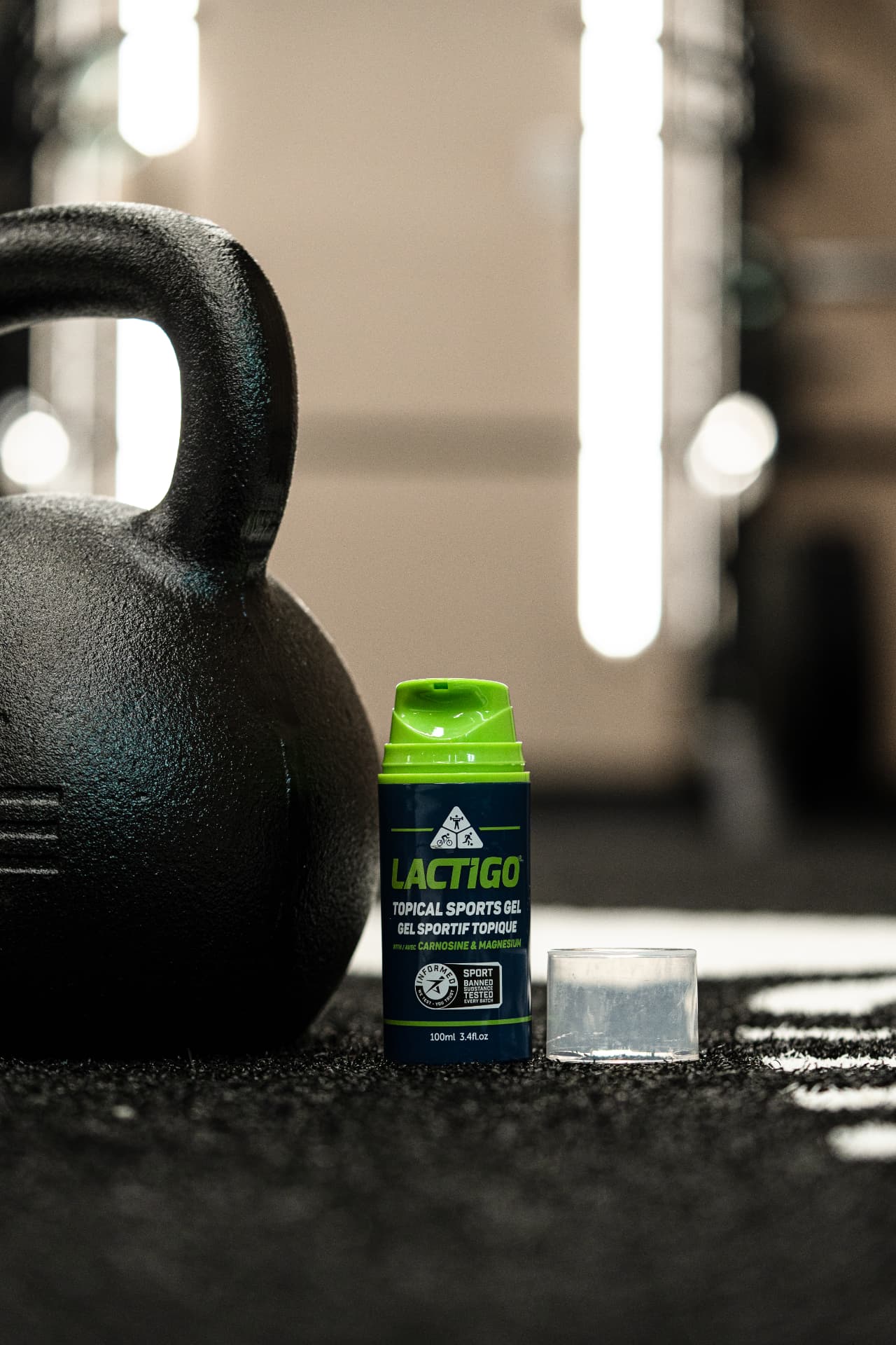 LactiGo bottle beside a black kettlebell in a dark gym environment