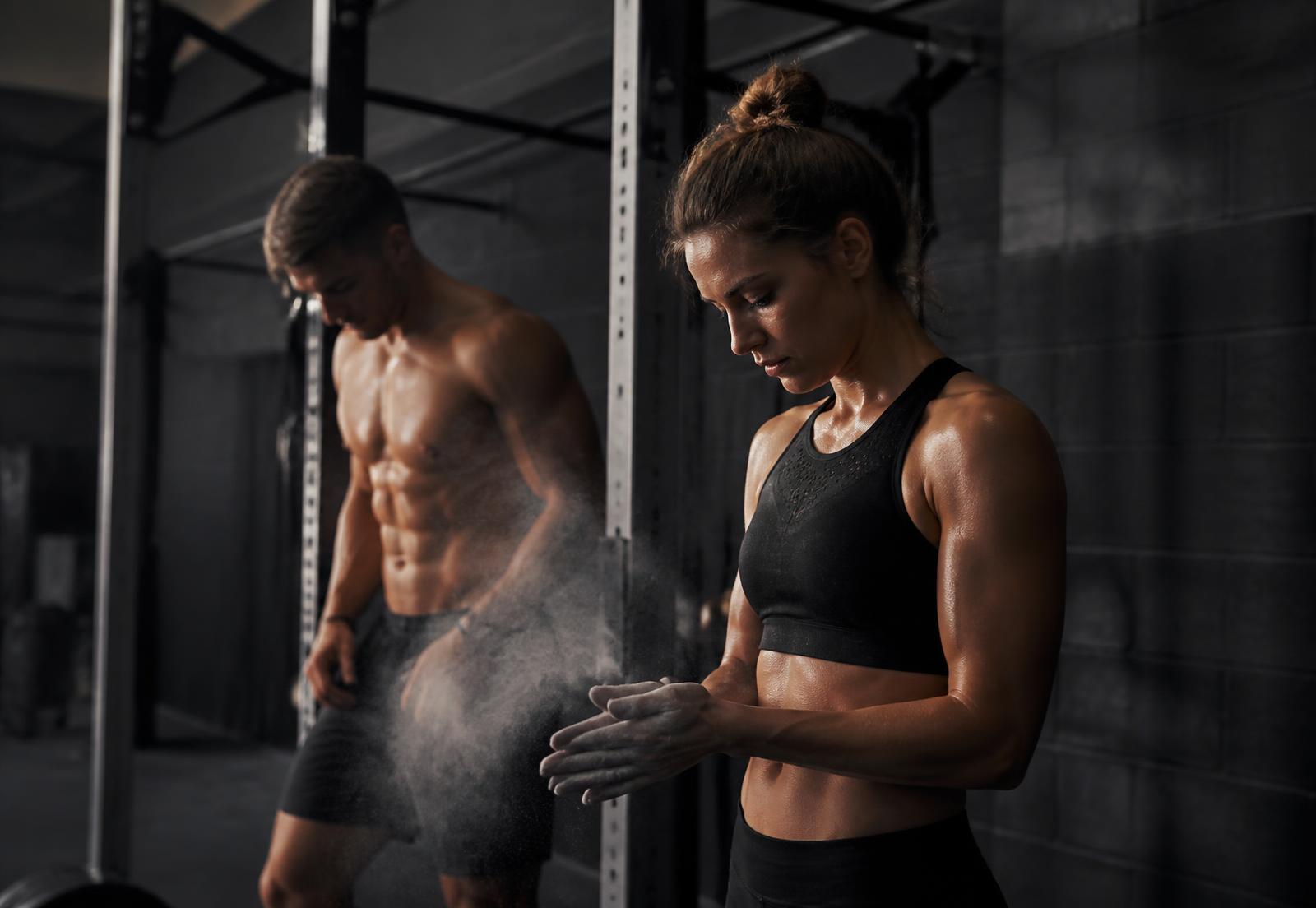 Two athletes preparing for a session in a dark industrial gym