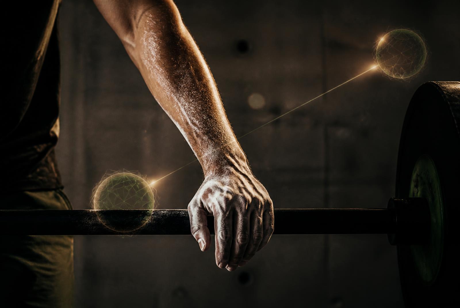 Chalked forearm resting on a barbell in a dark gym, with two faint points of light joined by a thin line